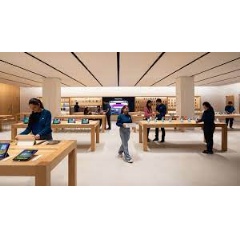 Customers enter Apple Saket though a uniquely designed curved storefront with white oak tables displaying Apples products and accessories.