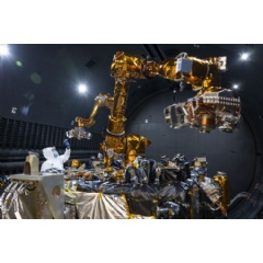 The robotics payload, including two robotic arms and electronics developed by the U.S. Naval Research Laboratory, and an engineer performing inspection. (Photo Credit: NRL)