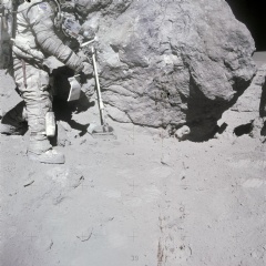 AS16-116-18653 (23 April 1972)  Astronaut Charles M. Duke Jr., Apollo 16 lunar module pilot, stands at a big rock adjacent (south) to the huge House Rock (barely out of view at right edge). 
NASA